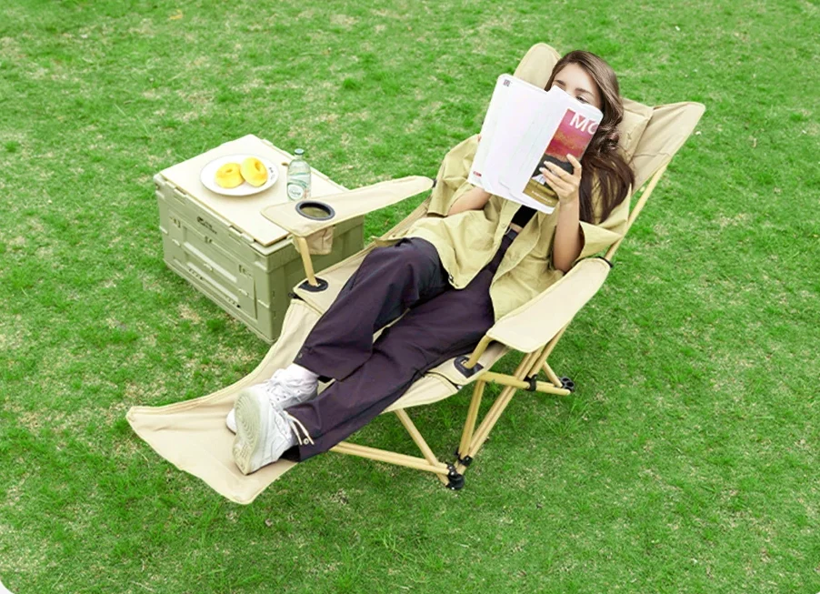 Girl relaxing and reading while sitting on reclining camping chair