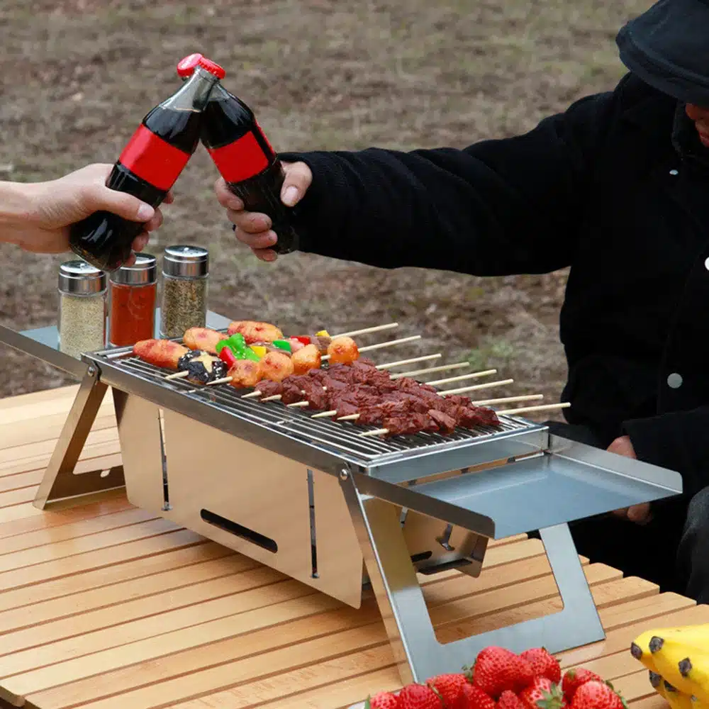 portable barbecue with two foldable stands that help you organize your utensils and ingredients for an outdoor fun experience